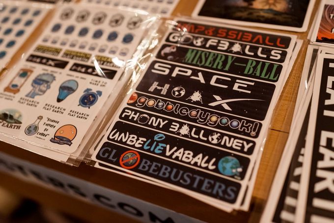 Flat Earth convention merchandise: sticker sheets featuring slogans like ‘Space Hoax’, ‘Globebusters’, ‘Research Flat Earth’, and other flat Earth catchphrases