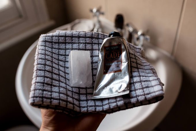 An alum block and L’Occitane Cade aftershave balm resting on a folded grey towel after shaving